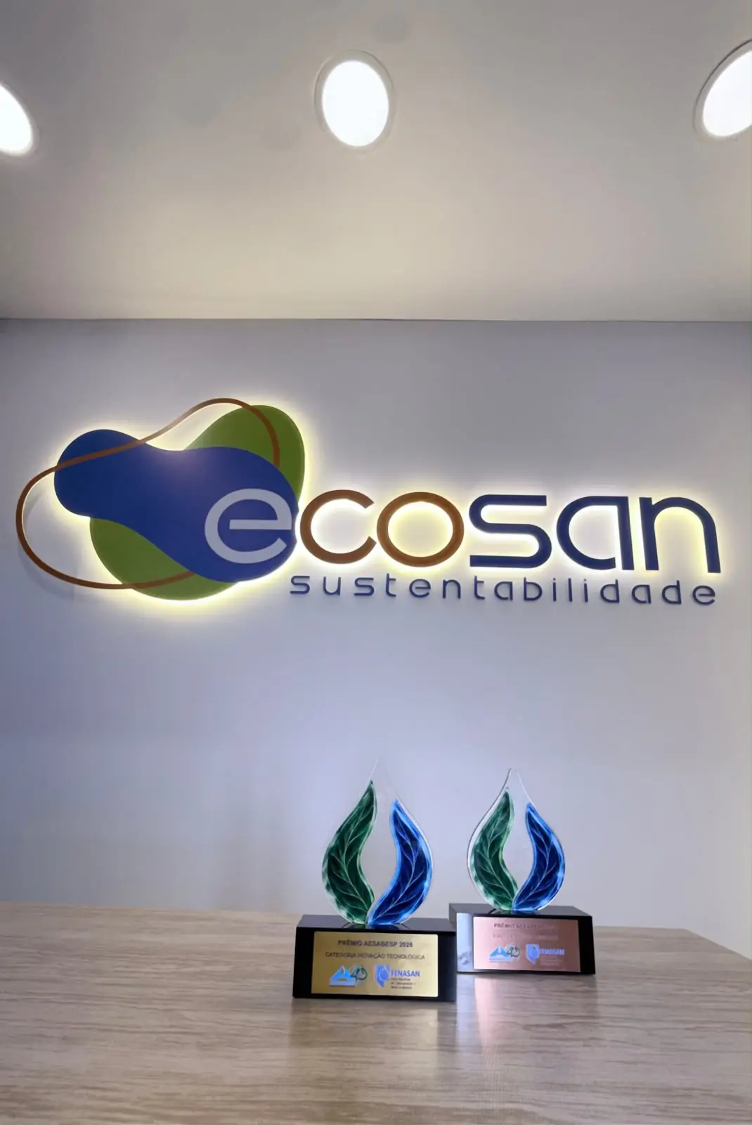 Os dois troféus do Prêmio AESabesp 2026 expostos na recepção da Ecosan, sob o logotipo da empresa